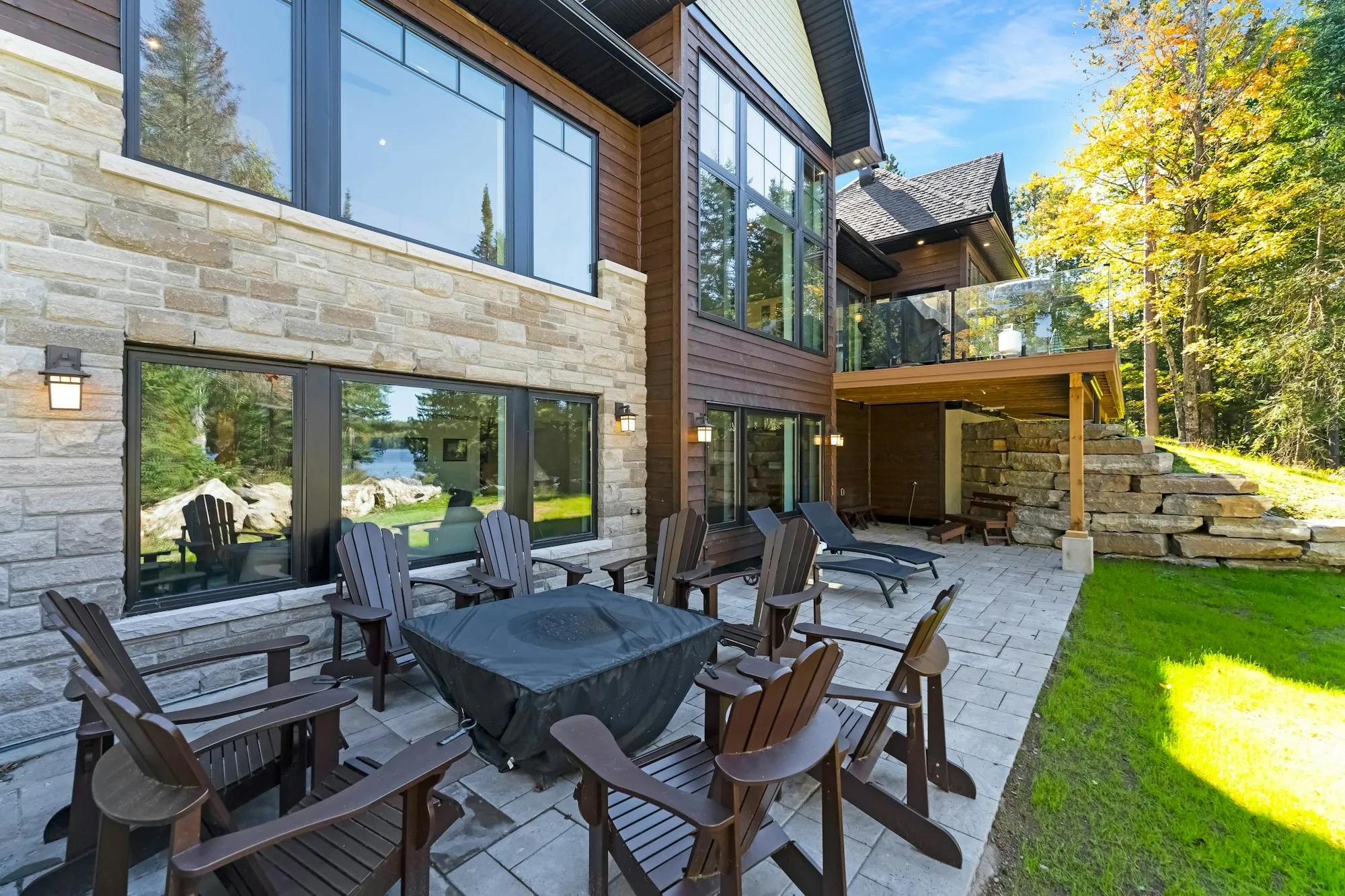 Patio dining set beside a modern stone house and lawn