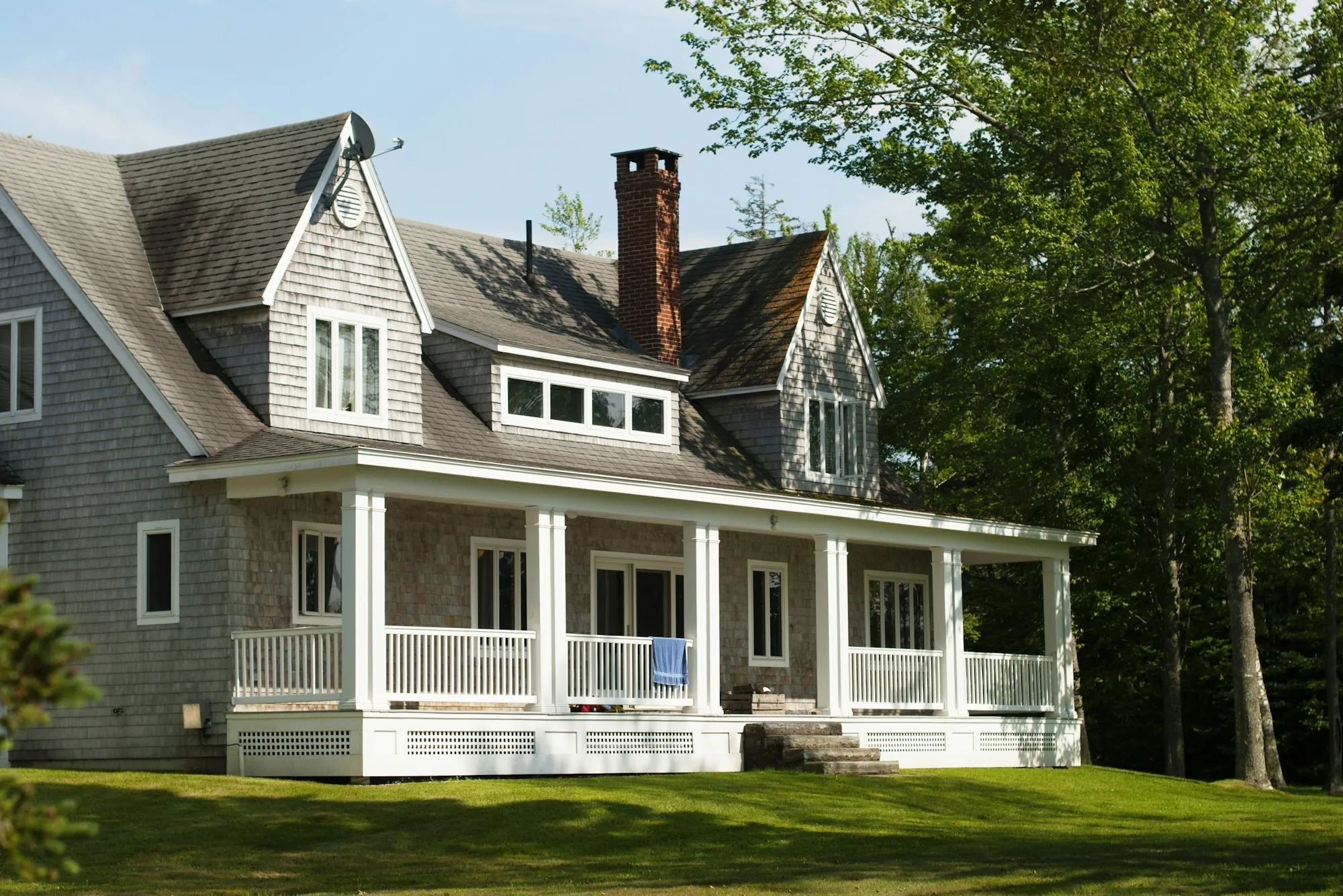 Shingled cottage home with a wraparound porch